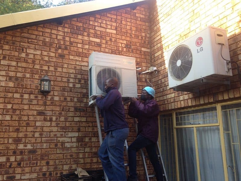 Two Panwell technicians installing an aircon unit